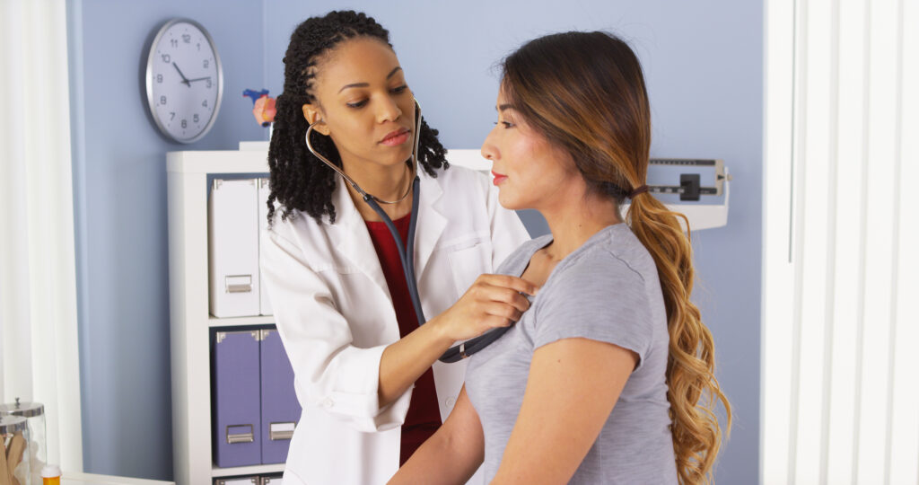 African American doctor listening to heart and lungs of patient