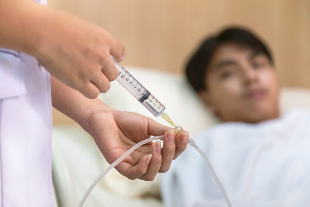 doctor or nurse giving medicine injection to iv tube for patient treatment at hospital.