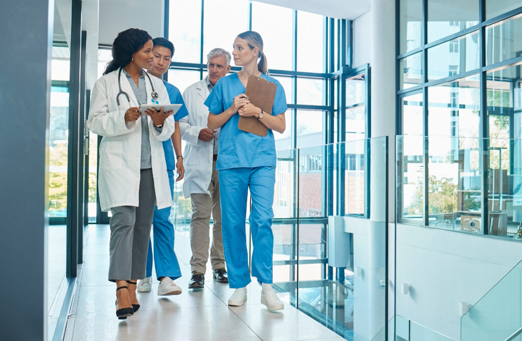 Hospital, doctors and nurses team walking with a tablet for a discussion, planning or research. Diversity men and women healthcare group talking about medical strategy, virus or surgery schedule